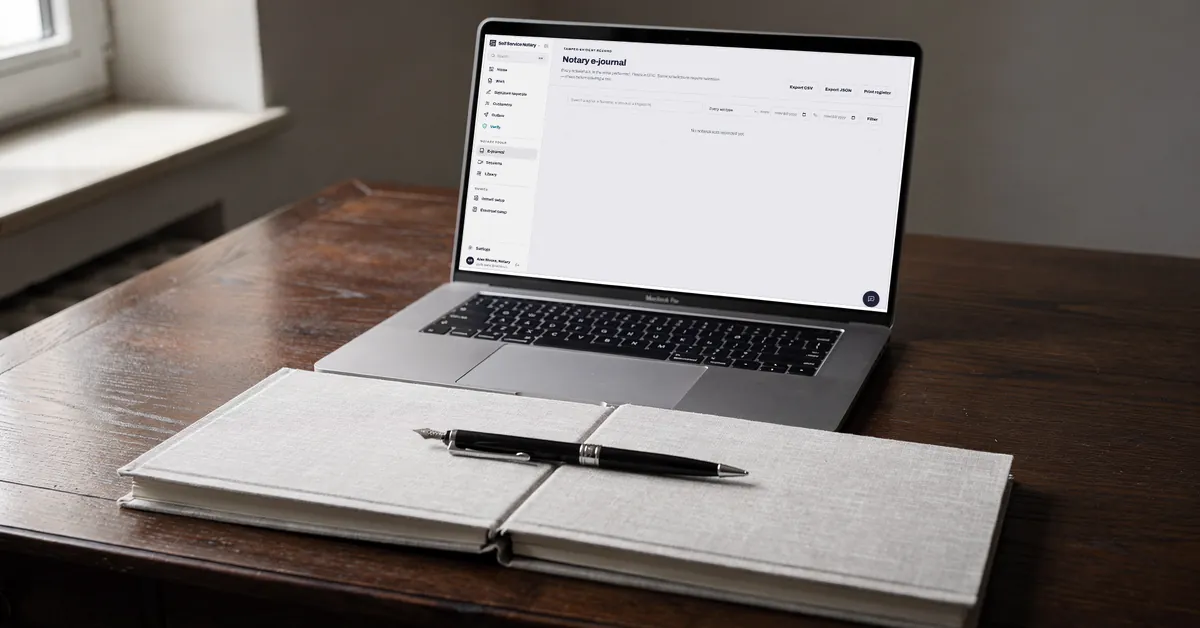 Una computadora portátil abierta en el registro electrónico notarial, sobre un escritorio junto a un registro en papel cerrado y un bolígrafo